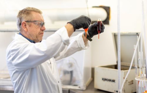 a man with white blouse in a lab holding two hard chrome plating chemical