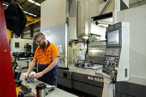 A person in an orange shirt working in a factory