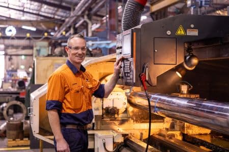 a man in an orange vest working on custom hydraulic cylinder specification