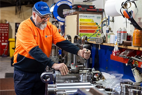 a man in an orange vest working on a fluid power equipment